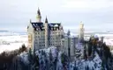 Neuschwanstein Castle on its hill above snowy forest