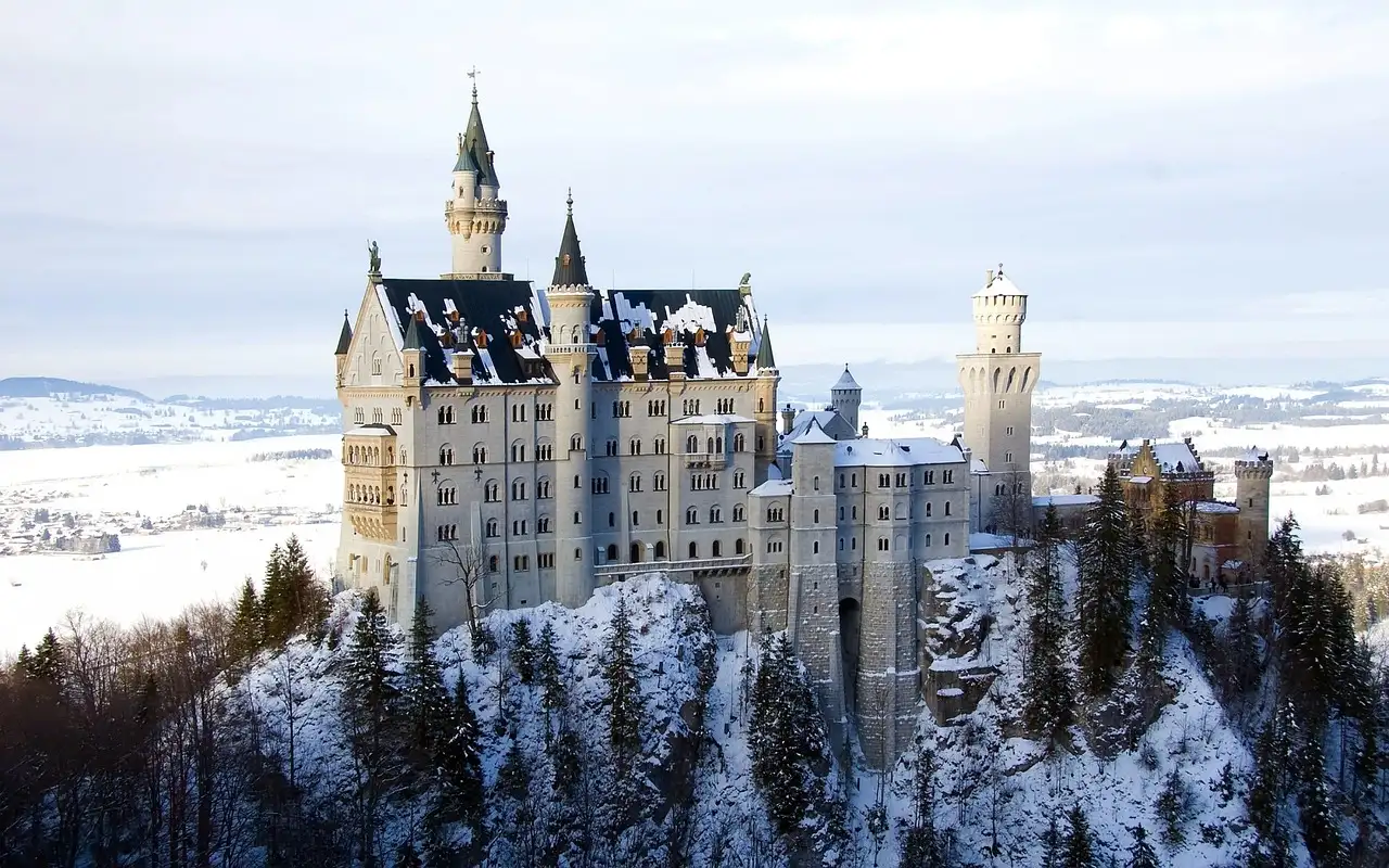 Neuschwanstein Castle on its hill above snowy forest
