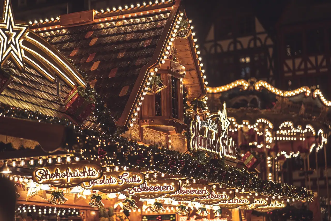 A wooden Christmas market stall lit with strings of lights at night