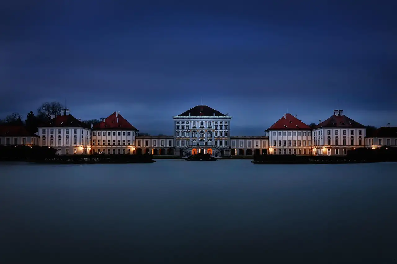 Nymphenburg Palace lit up at blue hour, reflected in the dark water in front of it