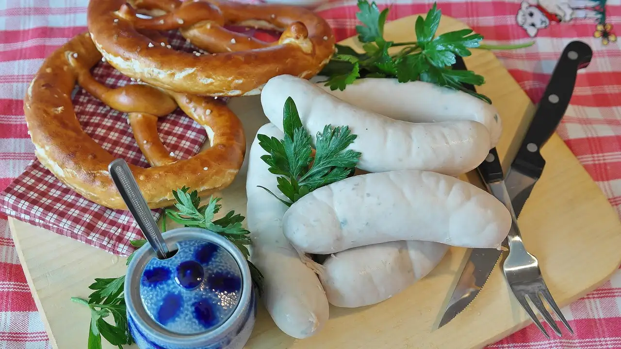 White sausages, a pretzel and sweet mustard on a wooden board