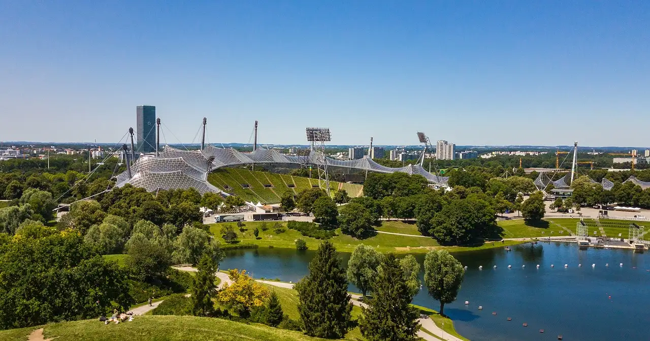 The tent-roof stadium and lake of Munich Olympic Park seen from above on a clear day