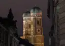 The two Frauenkirche towers lit up at night between dark Old Town buildings