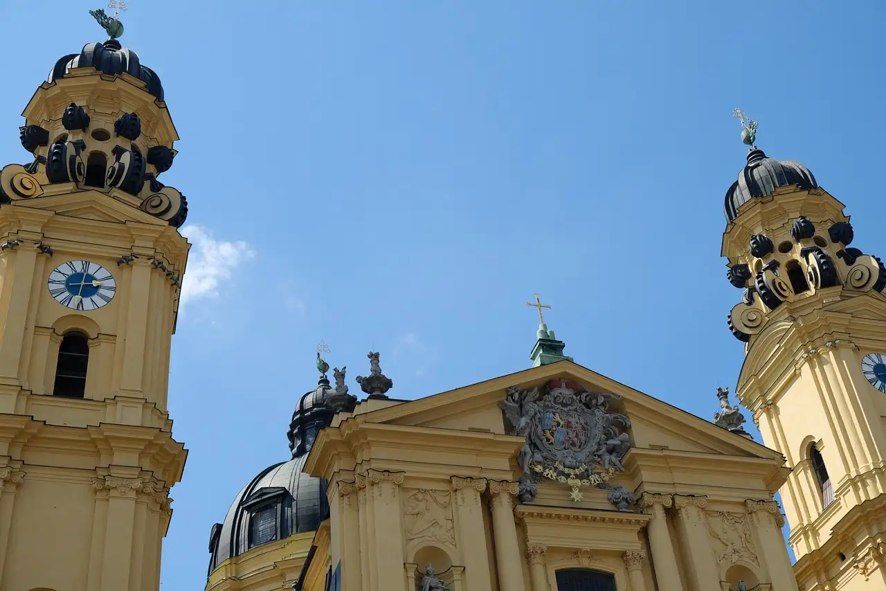 The yellow towers and dome of the Theatine Church in Munich against a blue sky