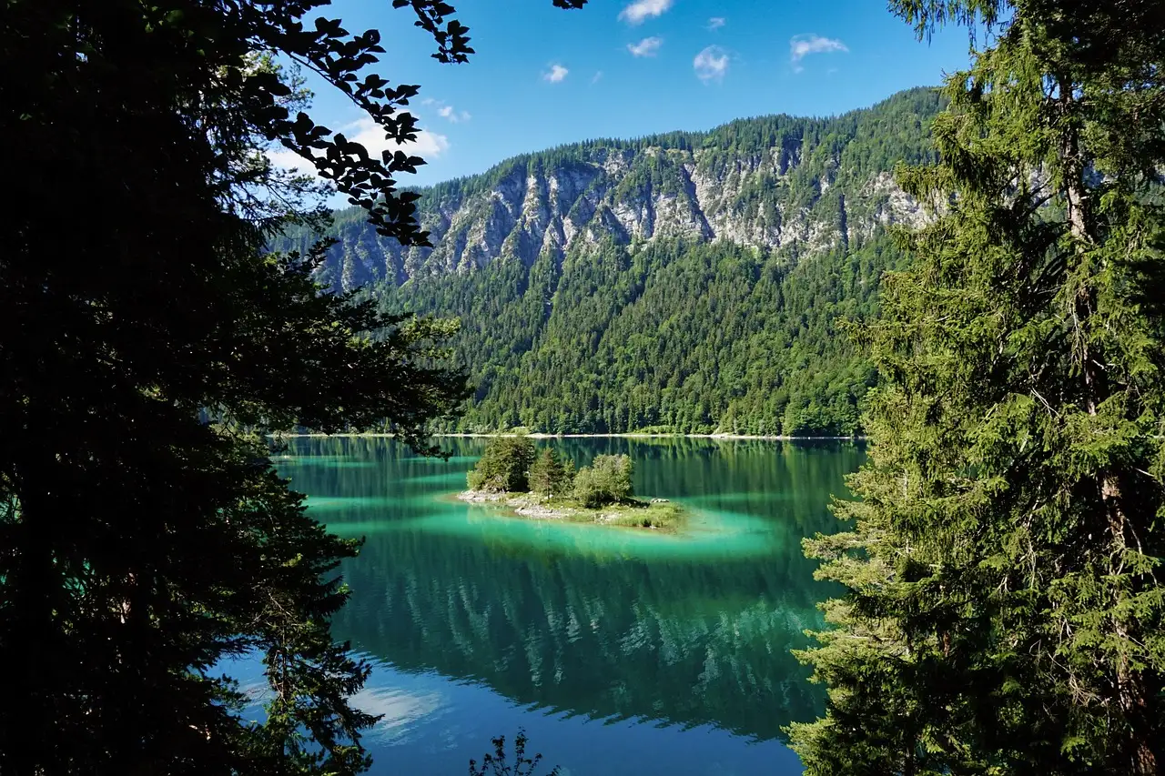 Lake Eibsee with clear green water and small wooded islands, framed by fir trees
