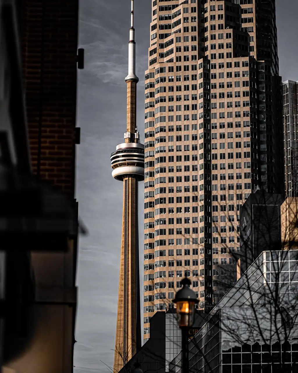 The CN Tower seen between downtown office towers on a grey day