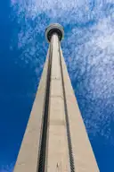 The concrete shaft of the CN Tower seen from its base against a blue sky