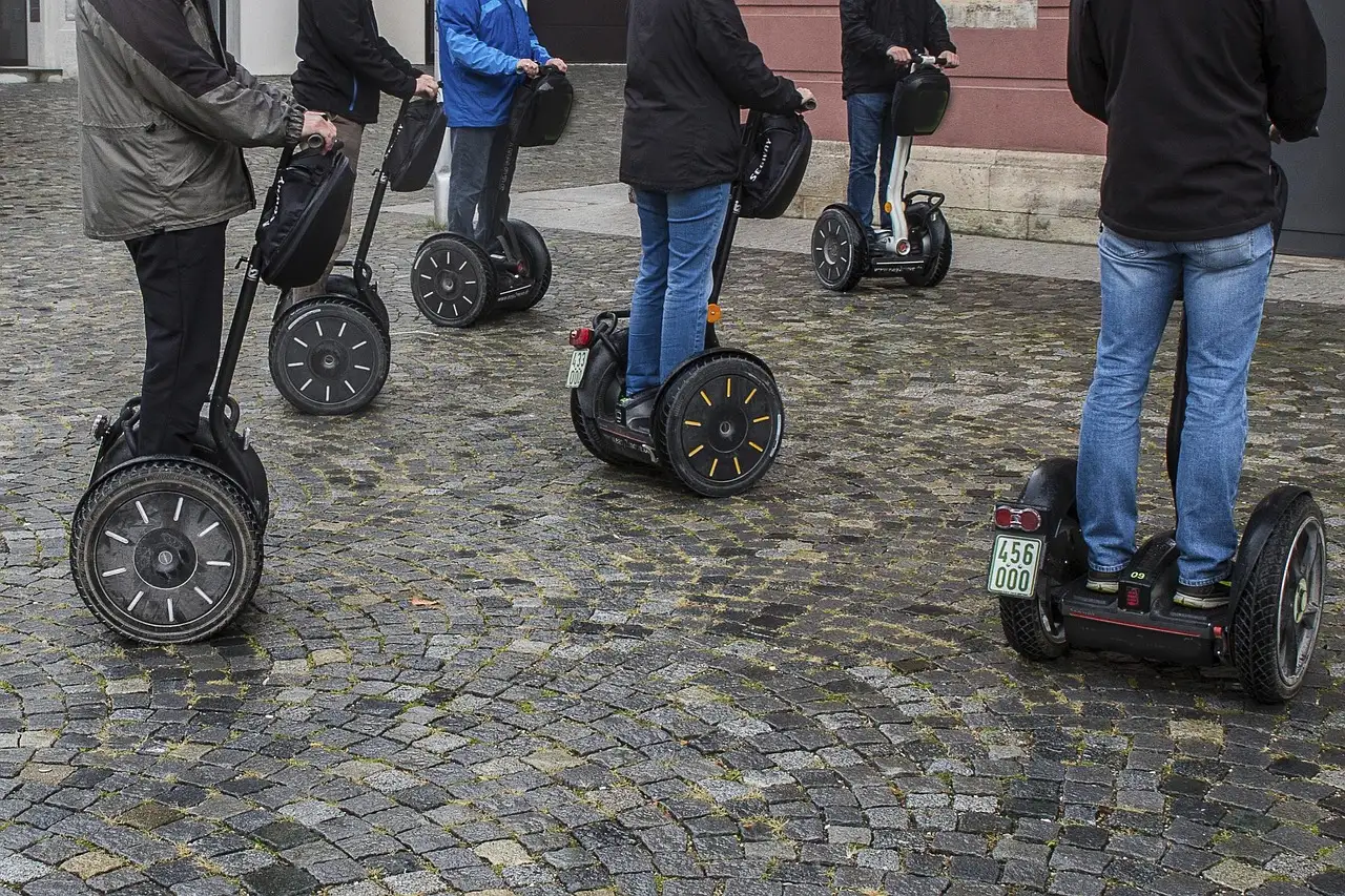 Segway riders standing on a cobbled square, seen from the waist down