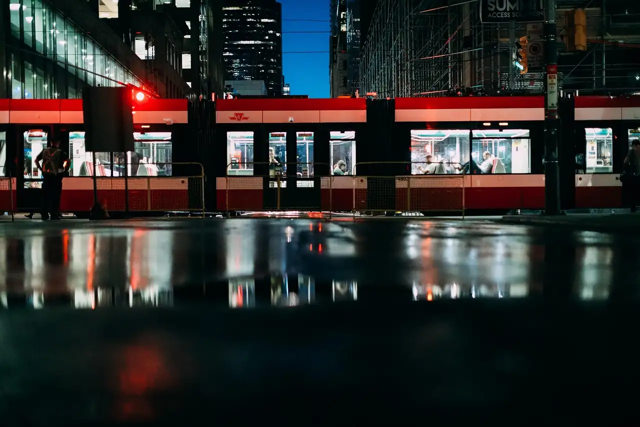 A red Toronto streetcar at night, reflected in a wet street