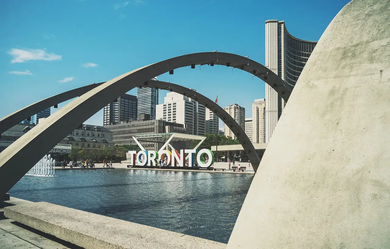 The curved towers of Toronto City Hall behind the arches and pool of Nathan Phillips Square