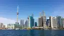 The CN Tower and waterfront apartment towers of downtown Toronto seen across the blue water of Lake Ontario.