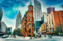 The red-brick Gooderham (Flatiron) Building at a downtown Toronto street corner, with tower blocks and pedestrians beside it.