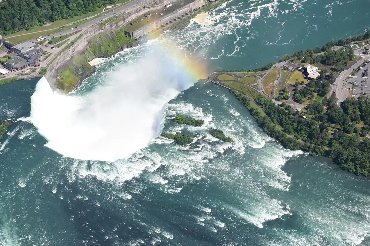 The Horseshoe Falls from high above, with a rainbow in the mist and roads along the river