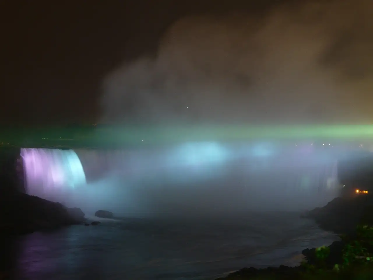 The Horseshoe Falls lit in purple and blue at night, with mist above