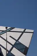 A corner of the Royal Ontario Museum's angular crystal-shaped wing, with metal panels and glass strips against a blue sky