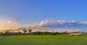 A football goalpost on a green field under a blue evening sky