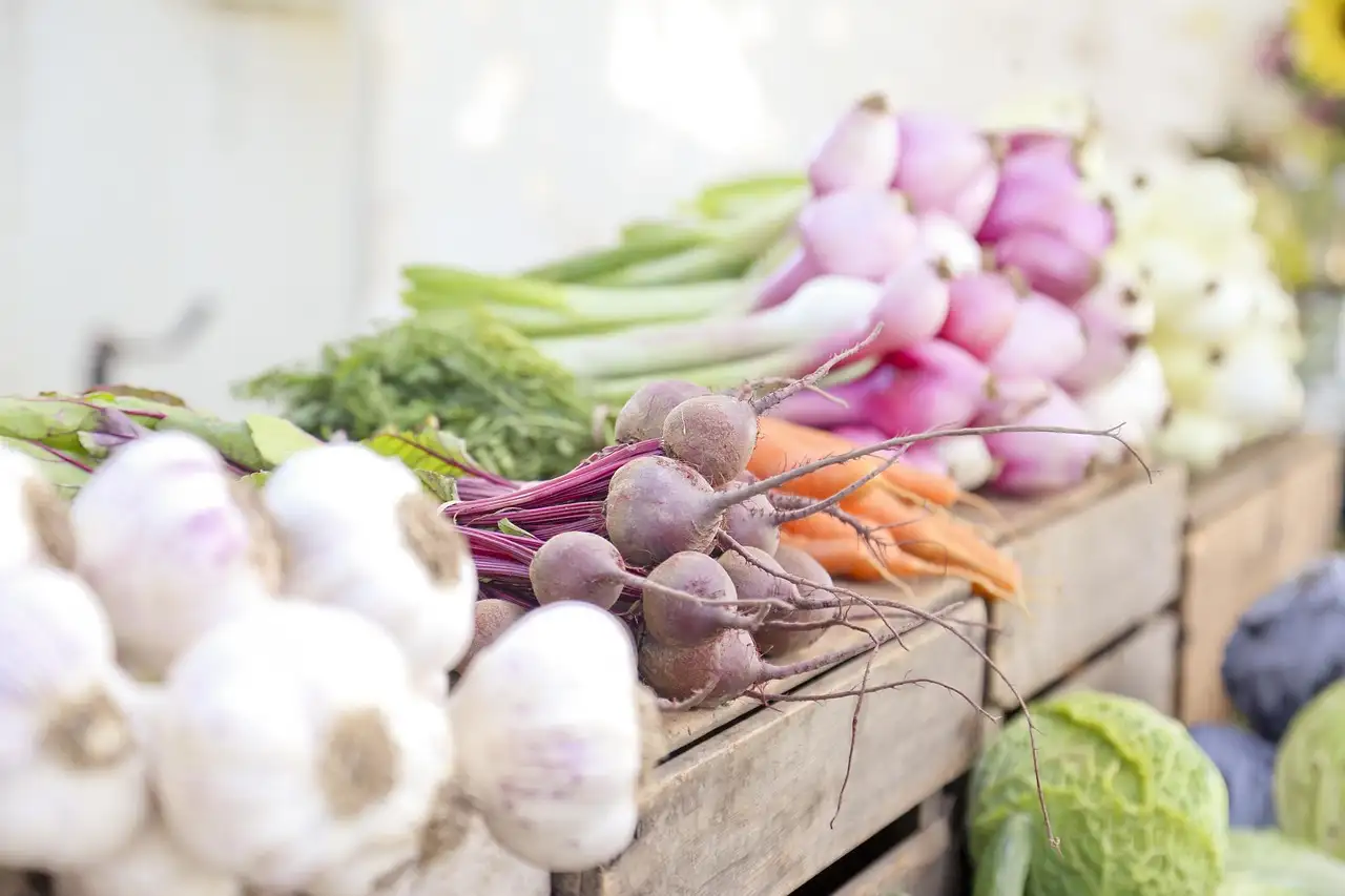 Garlic, beets and carrots in crates at a farmers market stand