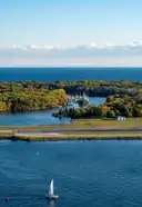 An aerial view of the wooded Toronto Islands, with a sailboat on the harbour