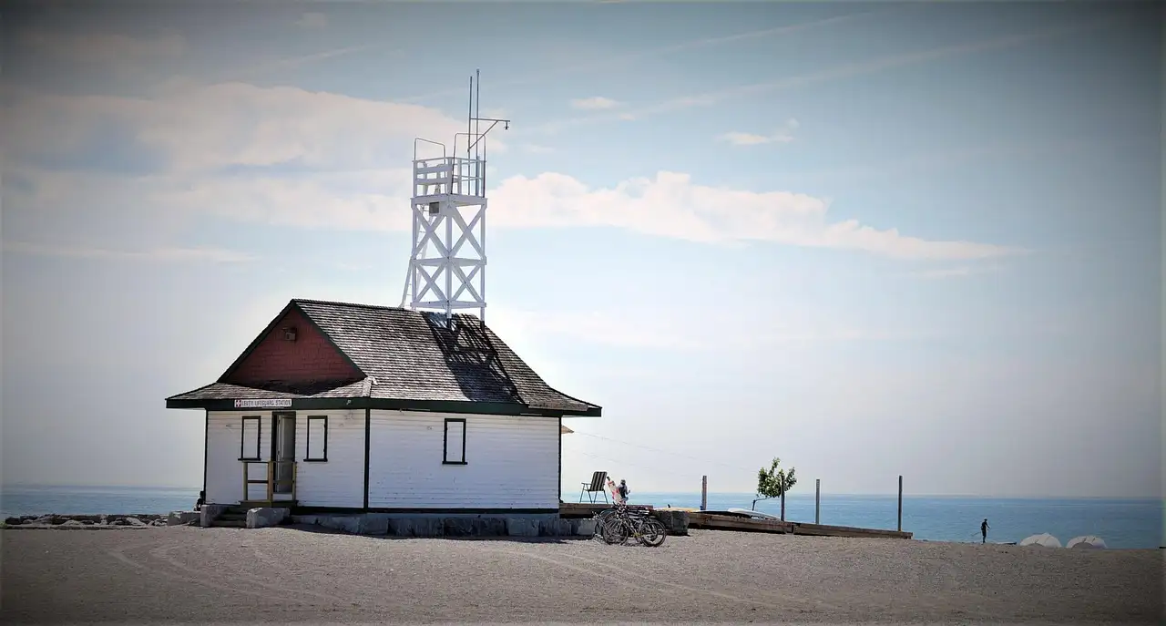 A white lifeguard hut on a sandy Toronto beach by the lake