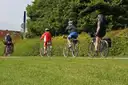A small group of cyclists in helmets riding along a park path