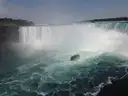 The Horseshoe Falls in a cloud of mist, with a tour boat on the river below