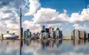 Downtown Toronto and the CN Tower under white clouds, reflected in still water